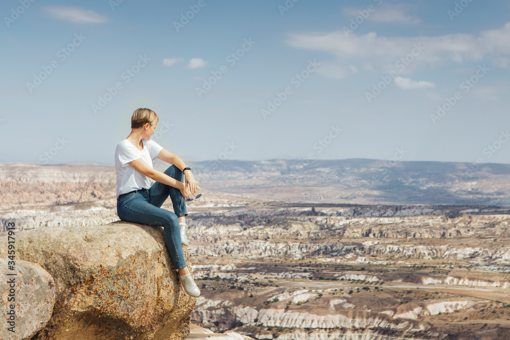 Traveler young woman sitting on a rock on mountain top with beautiful view under horizon, adventure Traveler young woman sitting on a rock on mountain top with beautiful view under horizon, adventure