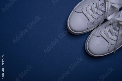 White sneakers on the classic blue background. Flat lay. Copy space. Place for text. Abstract surrealism and minimalism shopping concept.