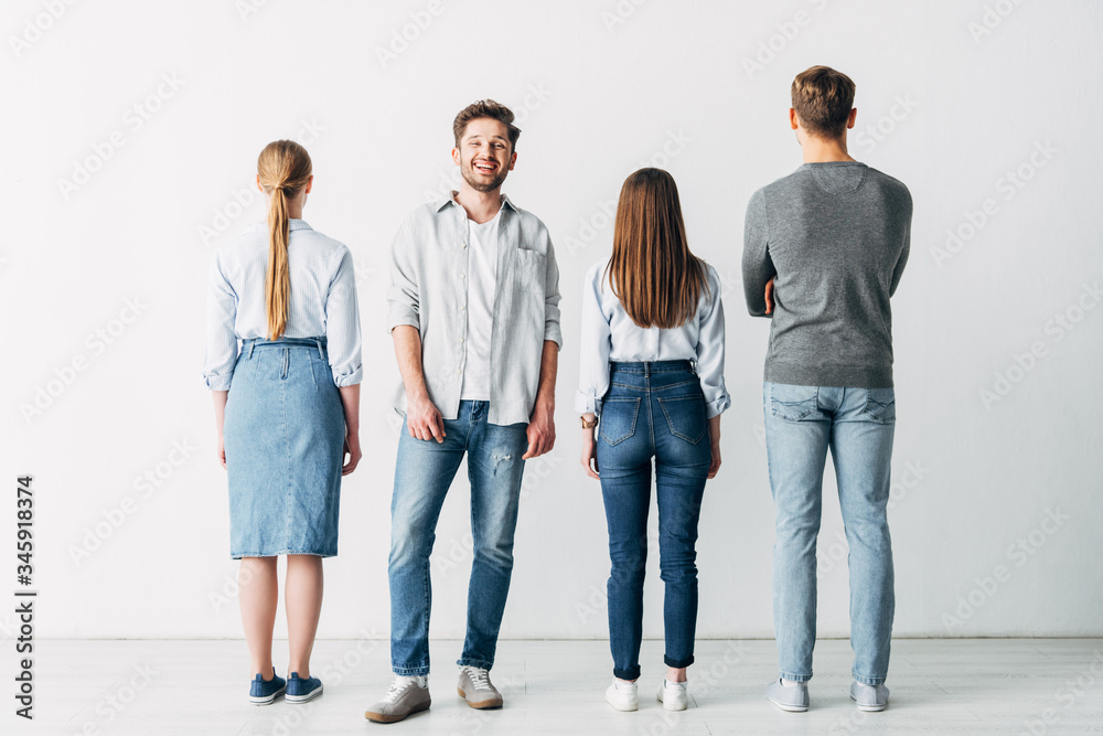 Smiling man looking at camera near employees in office Smiling man looking at camera near employees in office