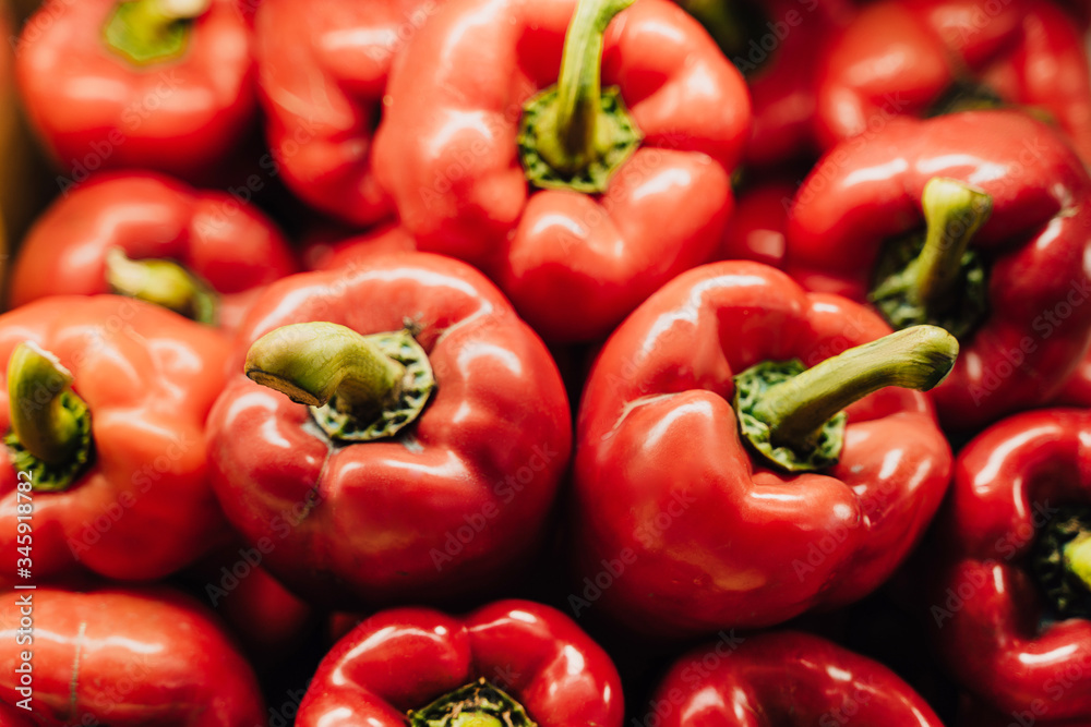 Piles of bell red peppers organized at the counter of a supermarket or grocery store.