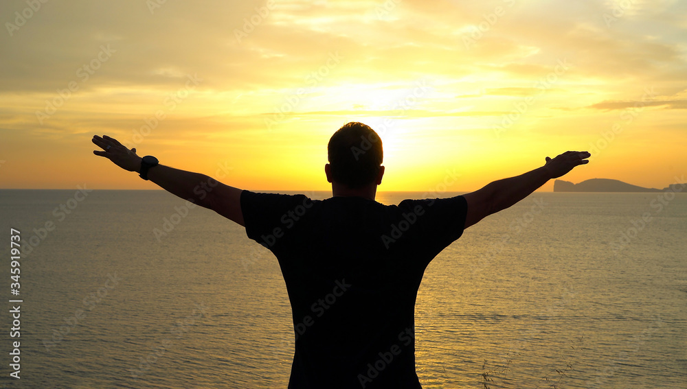 Silhouette of happy man open arms under the sunset