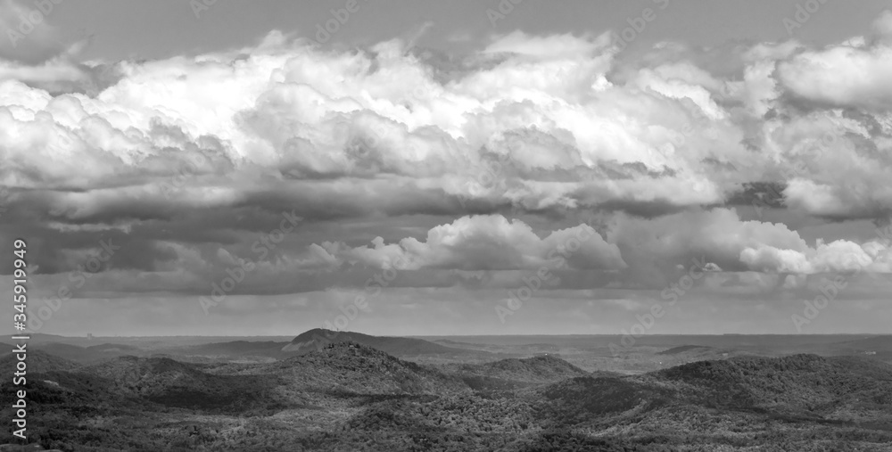 Layers of clouds casting shadows on hills in black and white