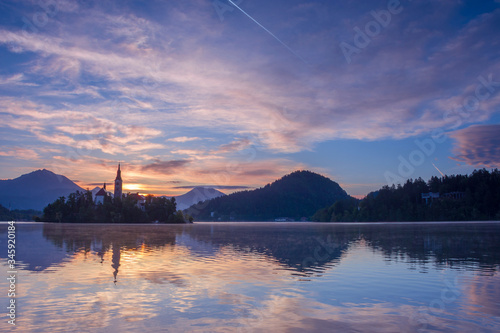 Beautiful sunrise and reflection at Lake Bled with the lake island and charming little church dedicated to the Assumption of Mary, famous tourist attraction in Slovenia © Aron M  - Austria