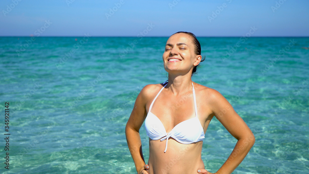 Portrait of happy woman in bikini sunbathing by turquoise sea, Sardinia, Italy,