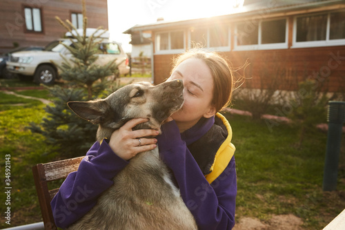 A girl admiring her dog in the country yard during selfisolation in the sunset