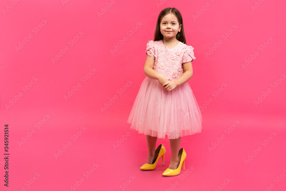 Fashionable cute young girl in big mother's yellow shoes on colored background. Fashionable cute young girl in big mother's yellow shoes on colored background.