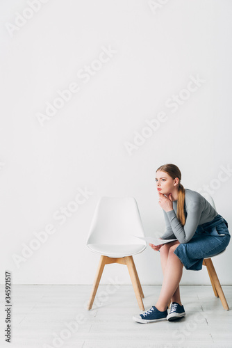 Side view of woman with resume looking away on chair in office