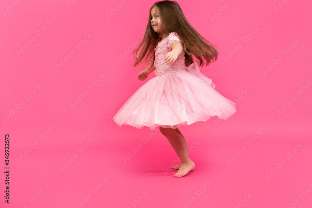 Cute little girl dreams of becoming a ballerina. Little Dancing Girl. Studio Shoot Over Pink Background Cute little girl dreams of becoming a ballerina. Little Dancing Girl. Studio Shoot Over Pink Background