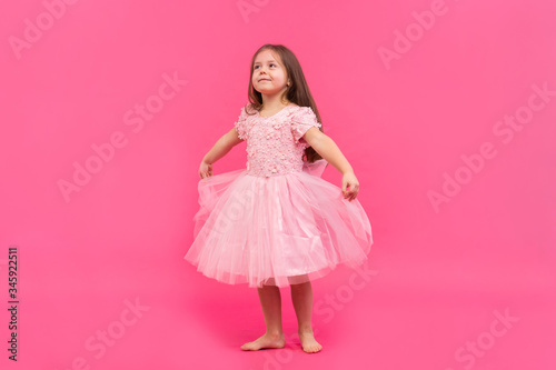 Cute little girl dreams of becoming a ballerina. Little Dancing Girl. Studio Shoot Over Pink Background