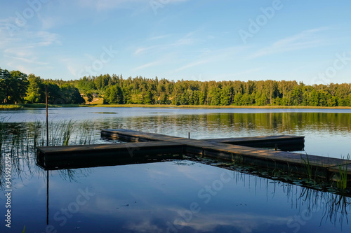 A small wooden pier on a forest lake. Scenic summer landscape. Trees on the shore.