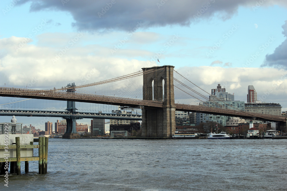 Obraz premium New york, USA - 20.12.2019: Brooklyn bridge in New York, Manhattan skyscrapers skyline behind across Hudson river at end of day New York, USA - stock photo