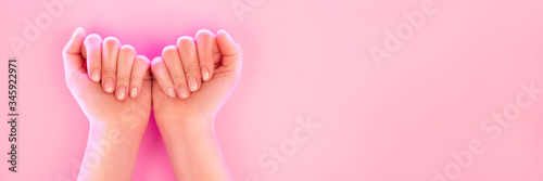 Woman's hands with perfect manicure in trendy neon light on pink background. Beauty concept.