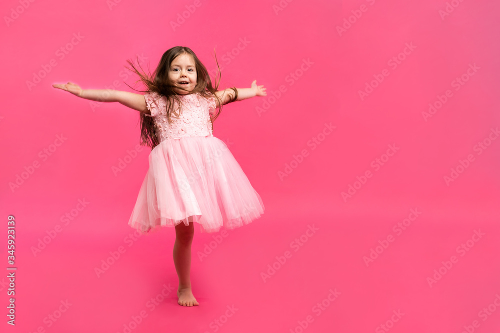 Cute little girl dreams of becoming a ballerina. Little Dancing Girl. Studio Shoot Over Pink Background Cute little girl dreams of becoming a ballerina. Little Dancing Girl. Studio Shoot Over Pink Background