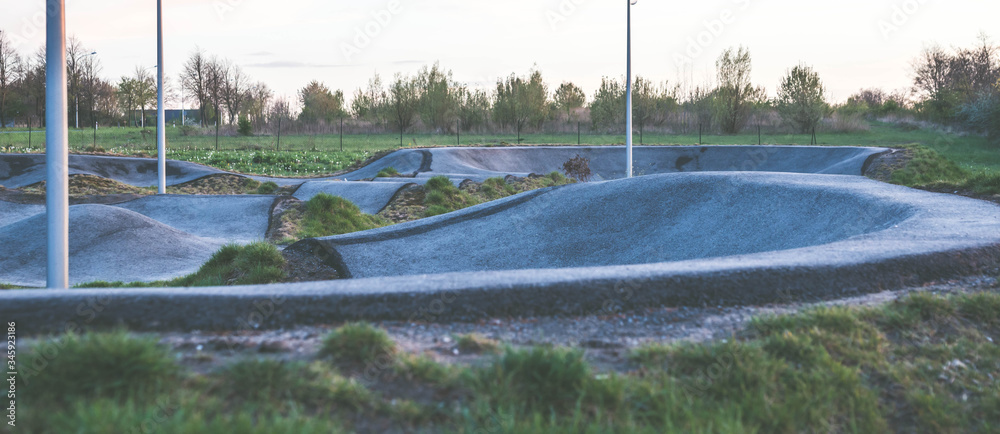 Empty skatepark in Poland, after sunset. Concrete bowls at playground.