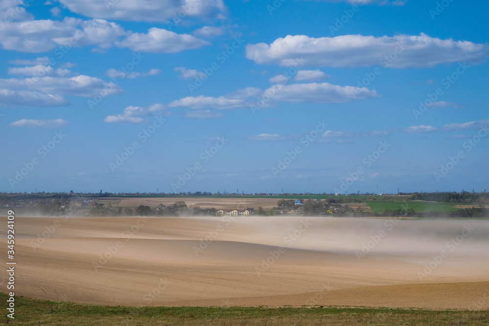 Dust storm on the field in Ukraine on the background of the village. Copy space.