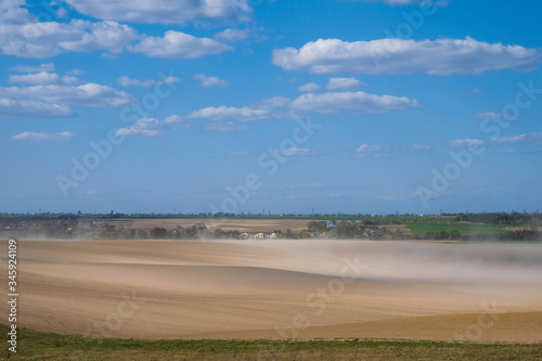 Dust storm on the field in Ukraine on the background of the village. Copy space.