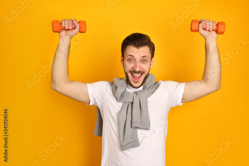A bearded young mandoing exercises with two dumbbells