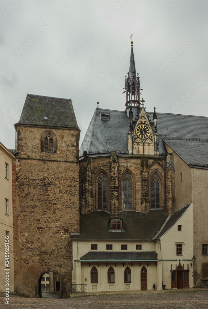Medieval fortress tower and bell tower in the Baroque style decorated with a clock. Altenburg. Germany. Soft focus, blurry background.
