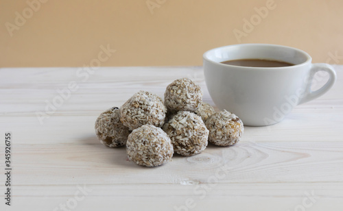 A healthy breakfast, protein balls or energy balls in a heap next to a white cup of coffee on a light background, good Monday, a snack at work