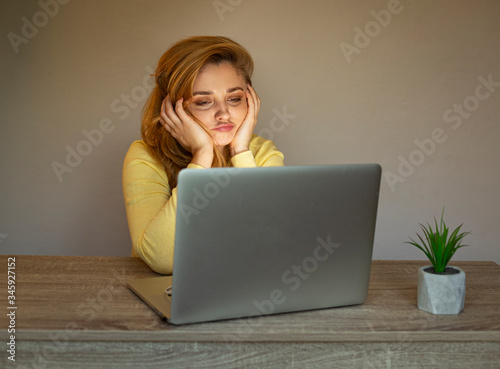 Girl with a laptop. Woman is bored with a laptop. Work online. Tired of working online.