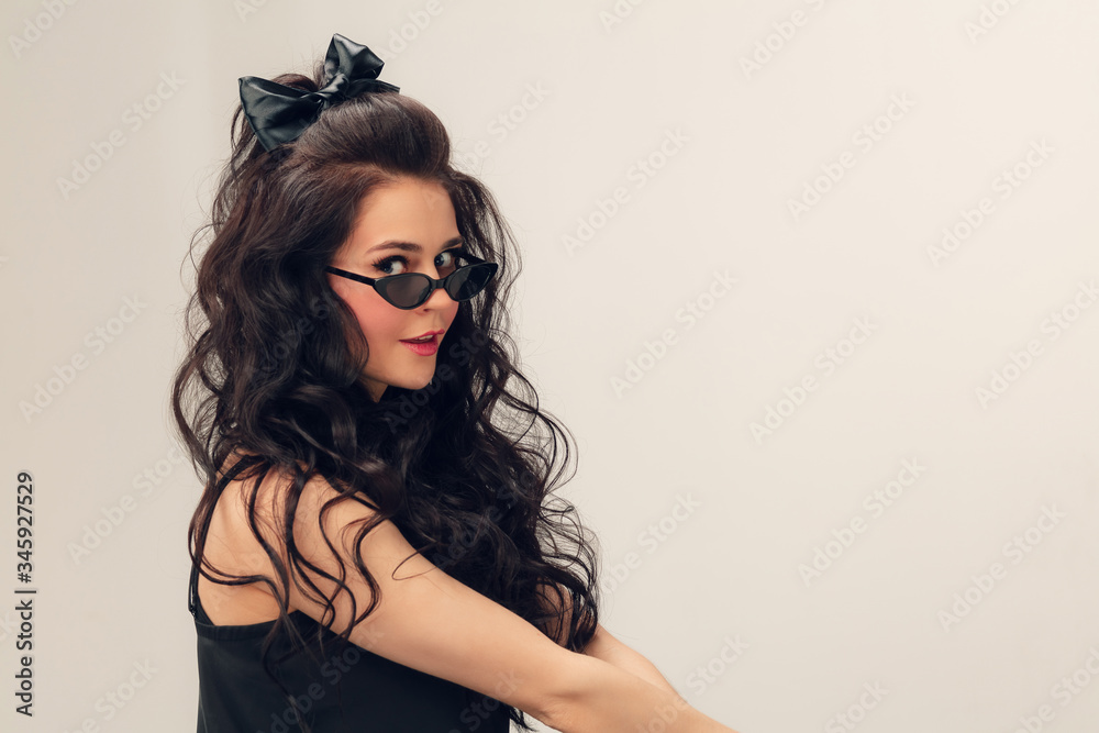 Wearing eyeglasses. Portrait of beautiful young woman on grey studio background. Caucasian cute brunette female model with long curly hair. Concept of beauty, fashion, cosmetics. Copyspace for ad. Wearing eyeglasses. Portrait of beautiful young woman on grey studio background. Caucasian cute brunette female model with long curly hair. Concept of beauty, fashion, cosmetics. Copyspace for ad.