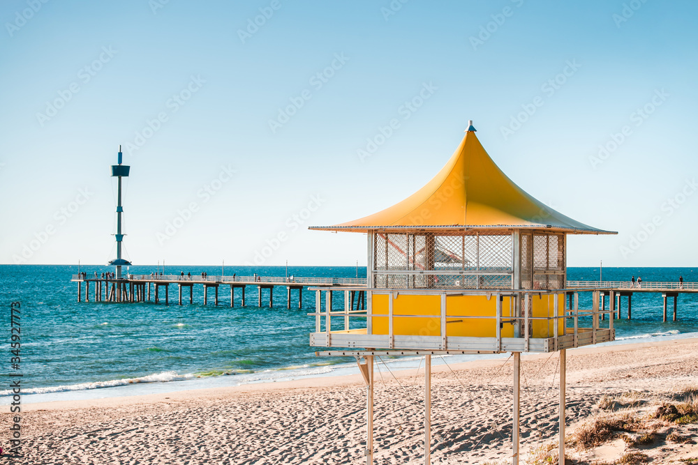Fototapeta premium Brighton surf life saving tower with people walking along the jetty on the background, South Australia