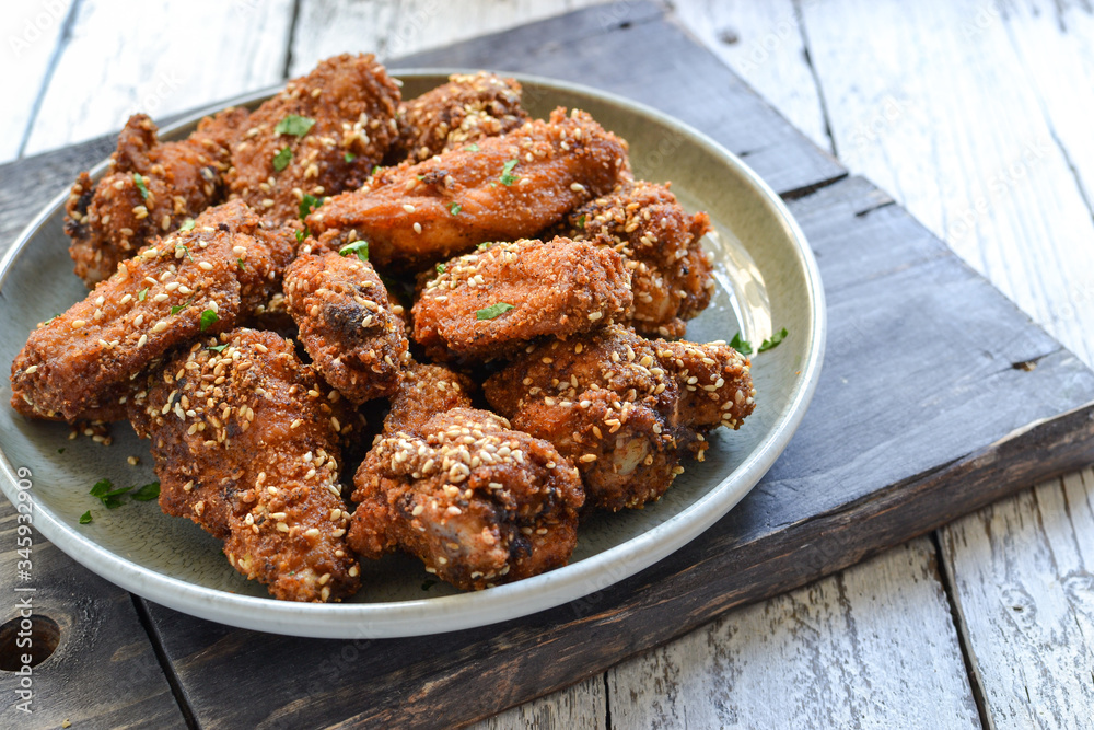 Baked chicken wings with sesame seeds. Ketchup and chili sauce. Free space for text. Wooden background. Delicious fried chicken wings. Close up Baked chicken wings with sesame seeds. Ketchup and chili sauce. Free space for text. Wooden background. Delicious fried chicken wings. Close up