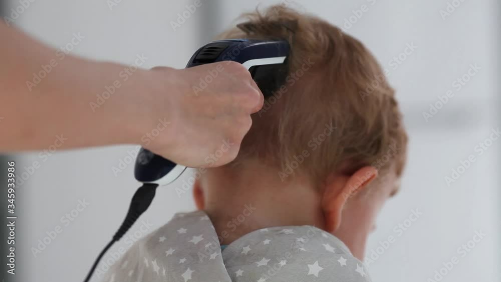 Children is haircut in the salon . Little boy trimmed with professional electric clipper machine in barbershop.