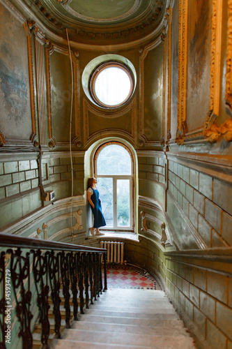 woman stands on sill of window in old house