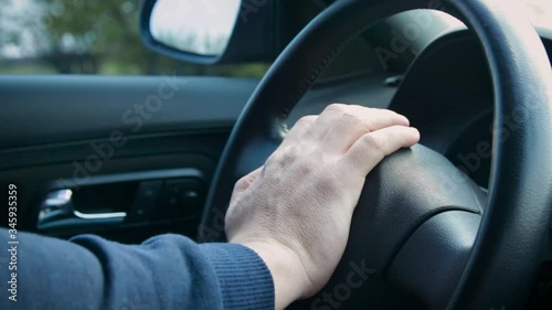 The hand of a man presses on the steering wheel of a car. Nervous unrecognized driver beeping in car. Technology and transportation concepts.