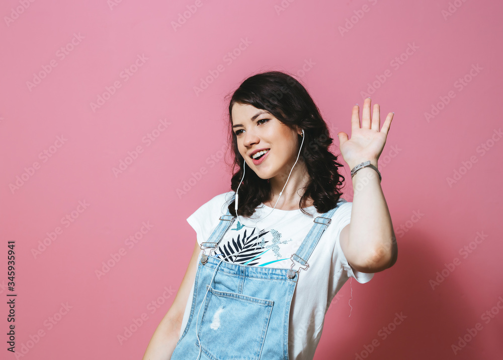 Image of happy Asian woman wearing earphones singing and dancing isolated over pink background Image of happy Asian woman wearing earphones singing and dancing isolated over pink background