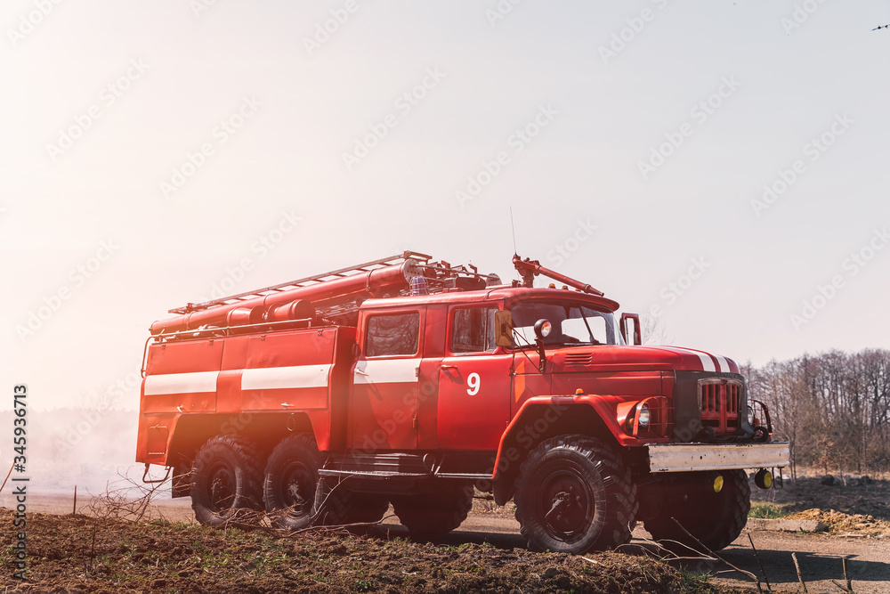 red firetruck on field with faded grass against sky. Concept of red firetruck on field with faded grass against sky. Concept of