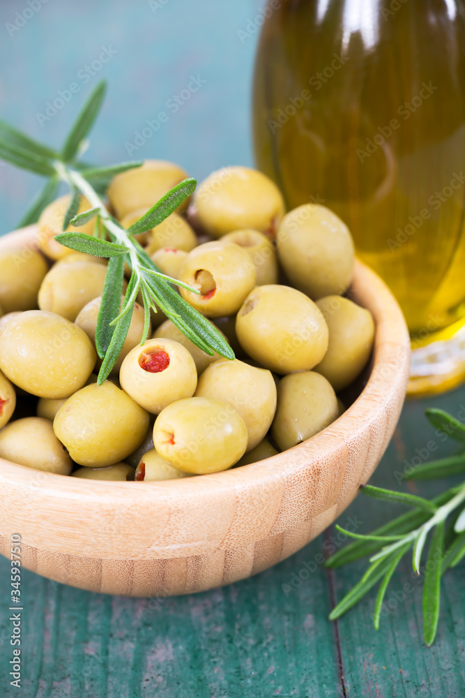 Fresh healthy green olives with rosemary and virgin oil in a bottle on wooden table Fresh healthy green olives with rosemary and virgin oil in a bottle on wooden table
