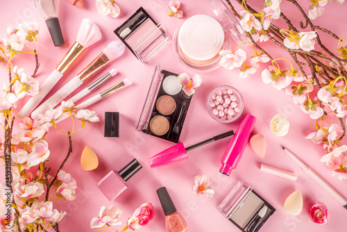 Makeup products with cosmetic bag and spring flowers. Professional Makeup set flatlay. Set of decorative cosmetics on tender pink background. Copy space above