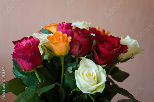 Lovely big colorful bouquet with many flowers  roses of red  vinous  orange and white colors. Green leaves and thorns. Still life. Calm pink background