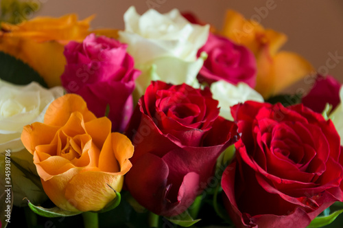 Lovely big colorful bouquet with many flowers  roses of red  vinous  orange and white colors. Green leaves and thorns. Still life. Calm pink background