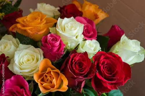 Lovely big colorful bouquet with many flowers  roses of red  vinous  orange and white colors. Green leaves and thorns. Still life. Calm pink background