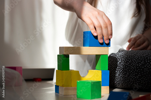 Multi-colored wooden block cubes stacked in a pyramid with defocused children hands.
