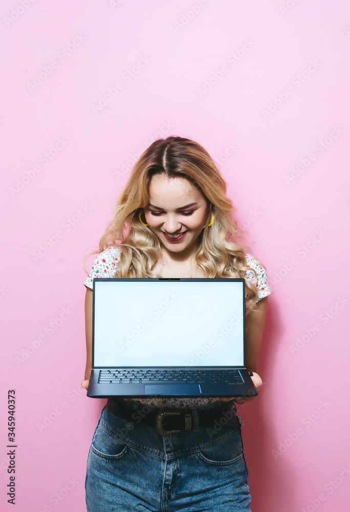 Portrait of a young girl holding a laptop and happy over pink background Portrait of a young girl holding a laptop and happy over pink background