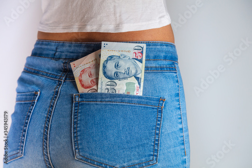 Fototapeta Naklejka Na Ścianę i Meble -  Singapore dollars banknote stuck in girls  jeans pocket