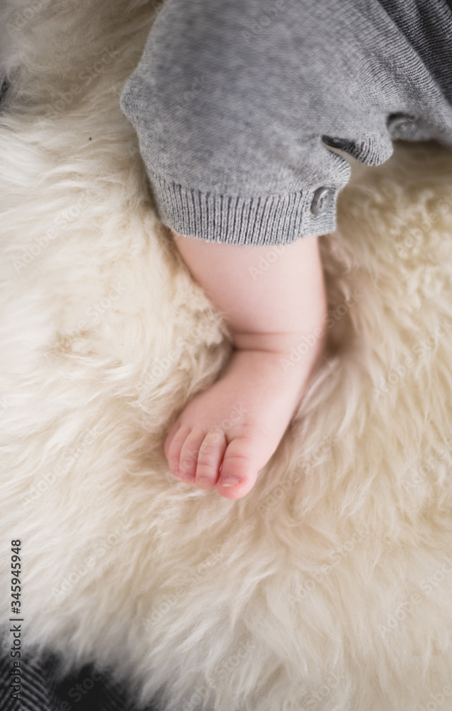 A beautiful soft delicate warm young baby foot photographed with a shallow depth of field. gentle calm colours and feel. baby care and well being. babies feet on a cream fur rug. A beautiful soft delicate warm young baby foot photographed with a shallow depth of field. gentle calm colours and feel. baby care and well being. babies feet on a cream fur rug.