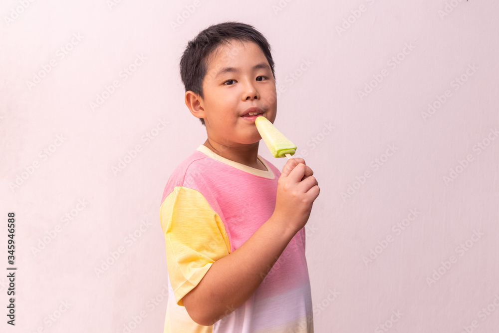 Asian boy eating a colorful frozen popsicle in the summer Asian boy eating a colorful frozen popsicle in the summer