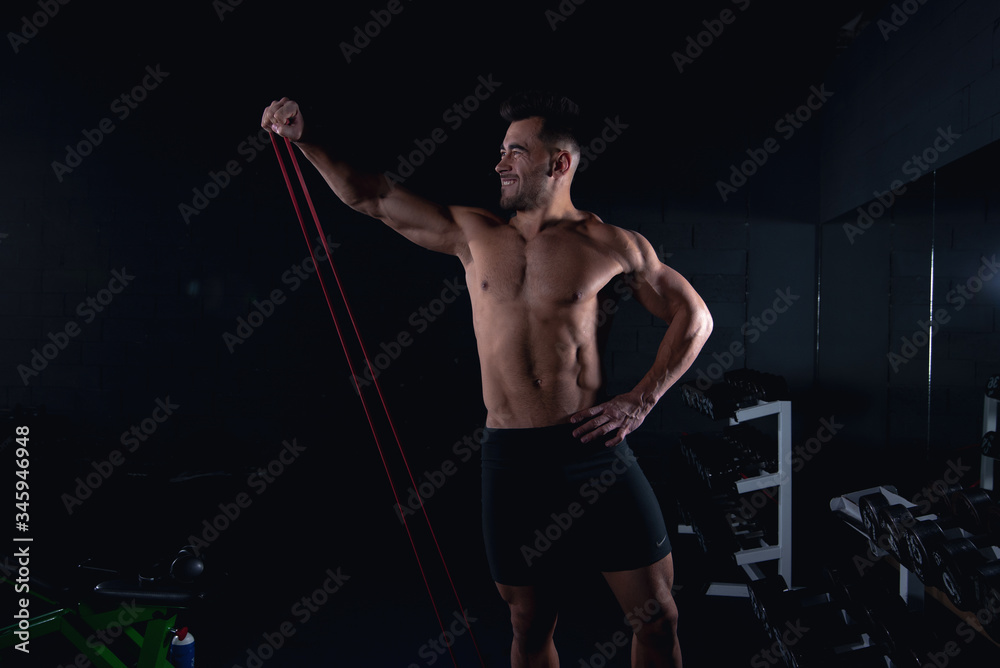 exercises with an elastic band shows a sporty man the gym, a sexy guy bodybuilder, sports lifestyle, home sports. exercises with an elastic band shows a sporty man the gym, a sexy guy bodybuilder, sports lifestyle, home sports.