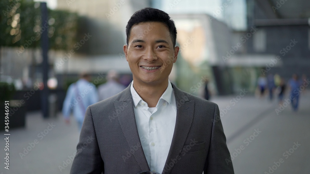 Portrait shot of a young happy Asian businessman smiling. The concept of success in career. Downtown district. Portrait shot of a young happy Asian businessman smiling. The concept of success in career. Downtown district.