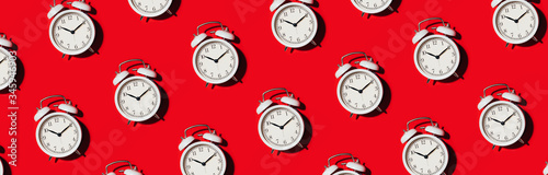 Pattern of white alarm clock on red background. Wake up alert concept. Morning routine. Back to school concept. Minimalist style design. Packing design. Creative design, minimal flat lay concept