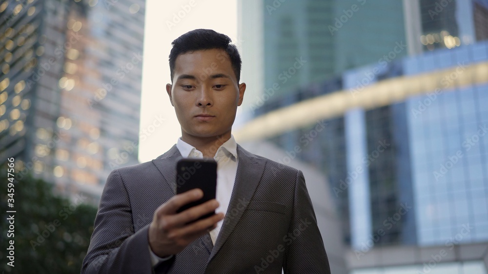 Front view of a young asian businessman, leading correspondence on the phone. Financial business area. Front view of a young asian businessman, leading correspondence on the phone. Financial business area.