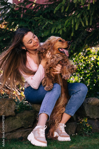 Beautiful young woman playing with her lovely dog on yard outdo