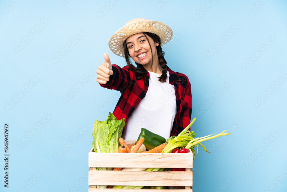 Young farmer Woman holding fresh vegetables in a wooden basket with thumbs up because something good has happened