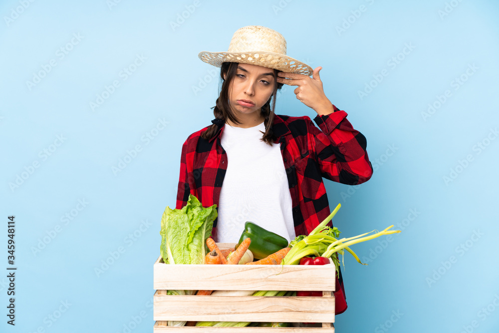 Young farmer Woman holding fresh vegetables in a wooden basket with problems making suicide gesture