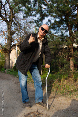 Happy senior man posing with a walking stick in sunny day
